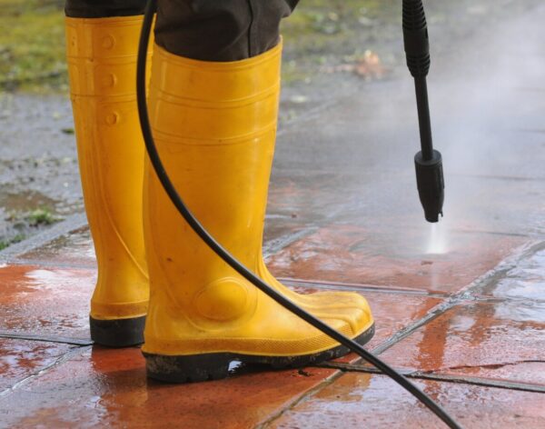 person-wearing-yellow-rubber-boots-with-high-pressure-water-nozzle-cleaning-dirt-tiles_181624-23652